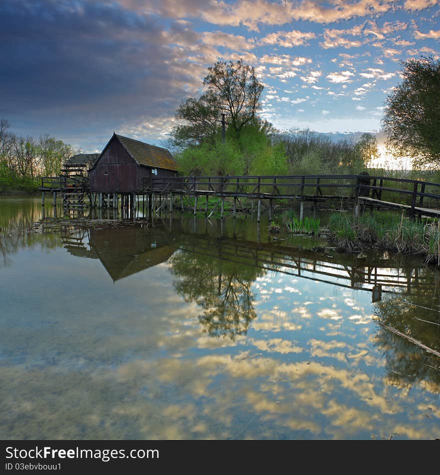 Clouds reflection in water with watermill