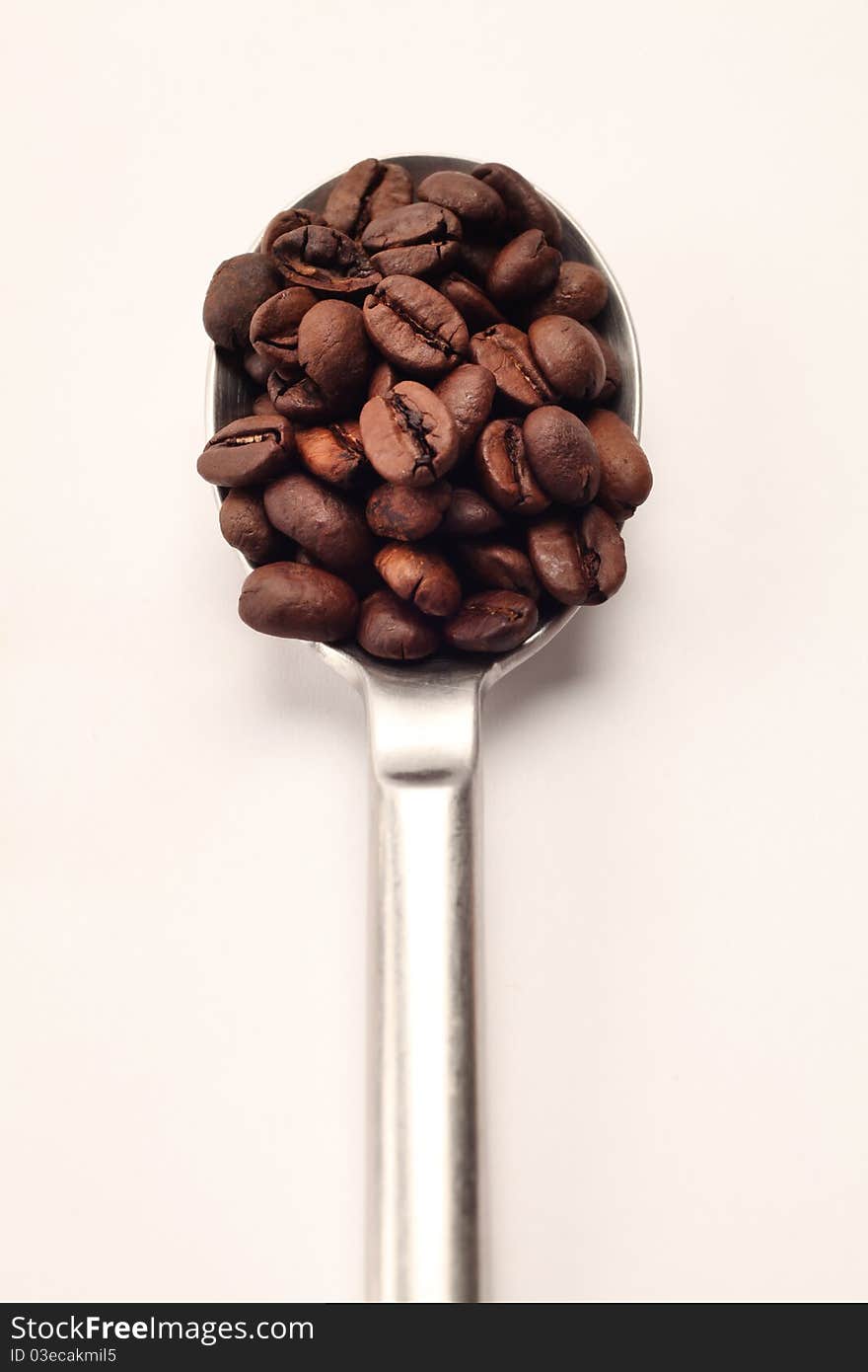 A spoon full of coffee beans. A spoon full of coffee beans.