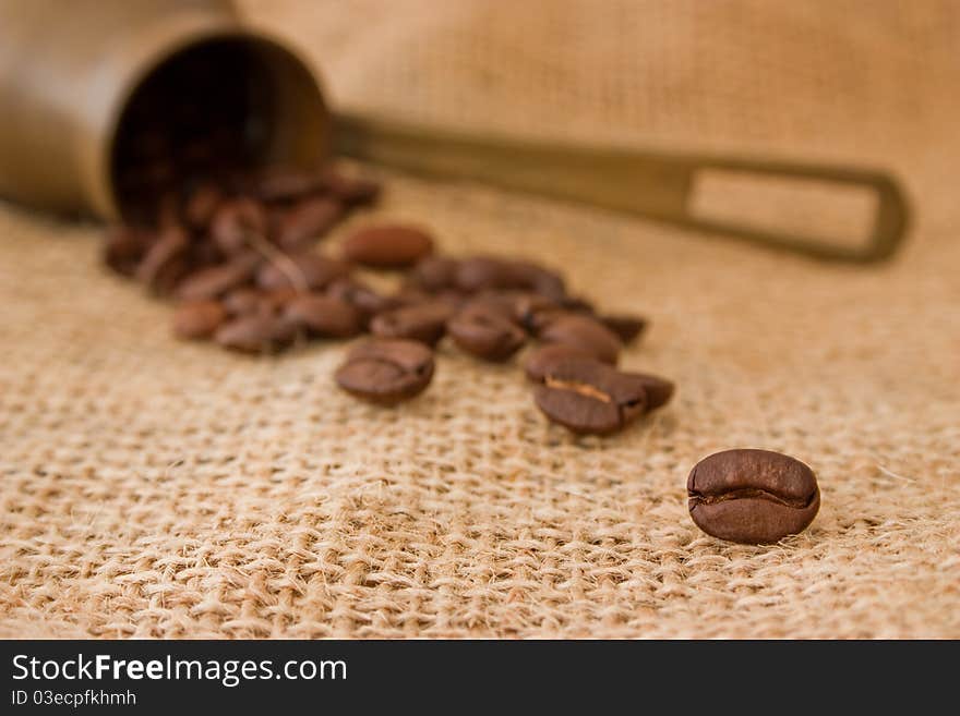 Coffee beans in a coffee pot on burlap sack background