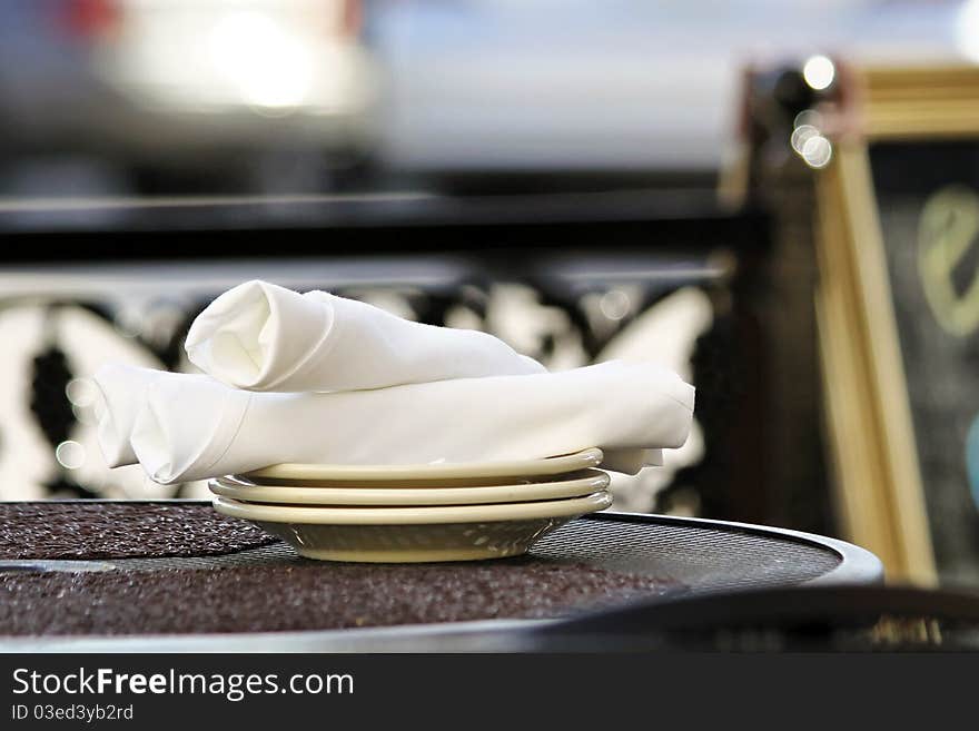 Stack of plates and napkins at an outdoor cafe.