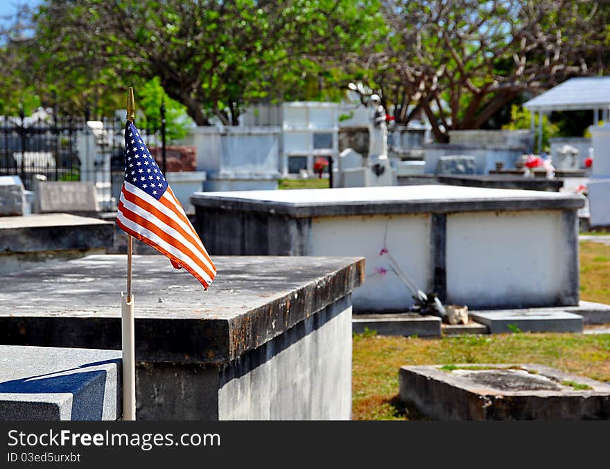 A Small American Flag Waves Over An Old Cemetery With Selective Focus On Flag. A Small American Flag Waves Over An Old Cemetery With Selective Focus On Flag