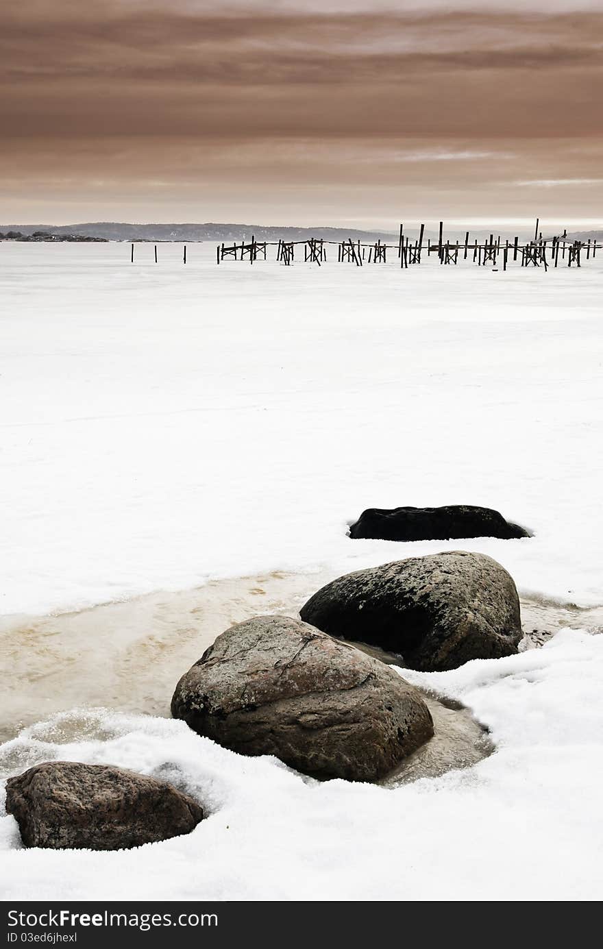 Pier And Stones In Frozen Sea