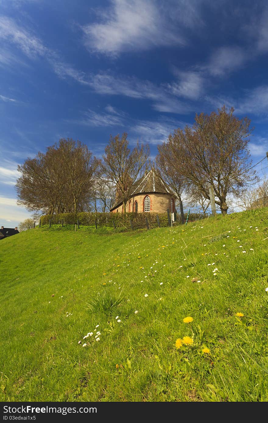 Old church on a high hill surrounded with trees with grass and some flowers in the foreground. Old church on a high hill surrounded with trees with grass and some flowers in the foreground