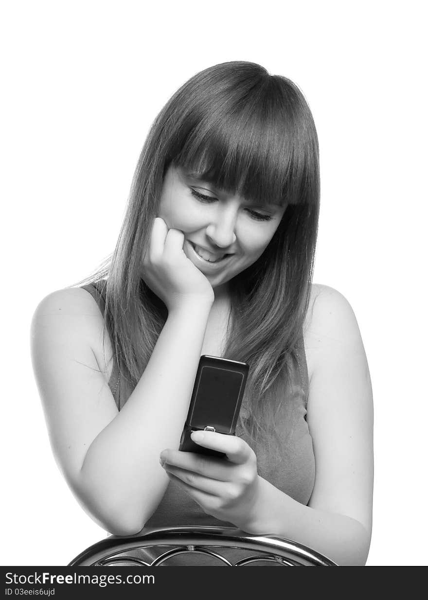 Black-and-white portrait of the long-haired girl with a thoughtful smile looking at phone. Black-and-white portrait of the long-haired girl with a thoughtful smile looking at phone