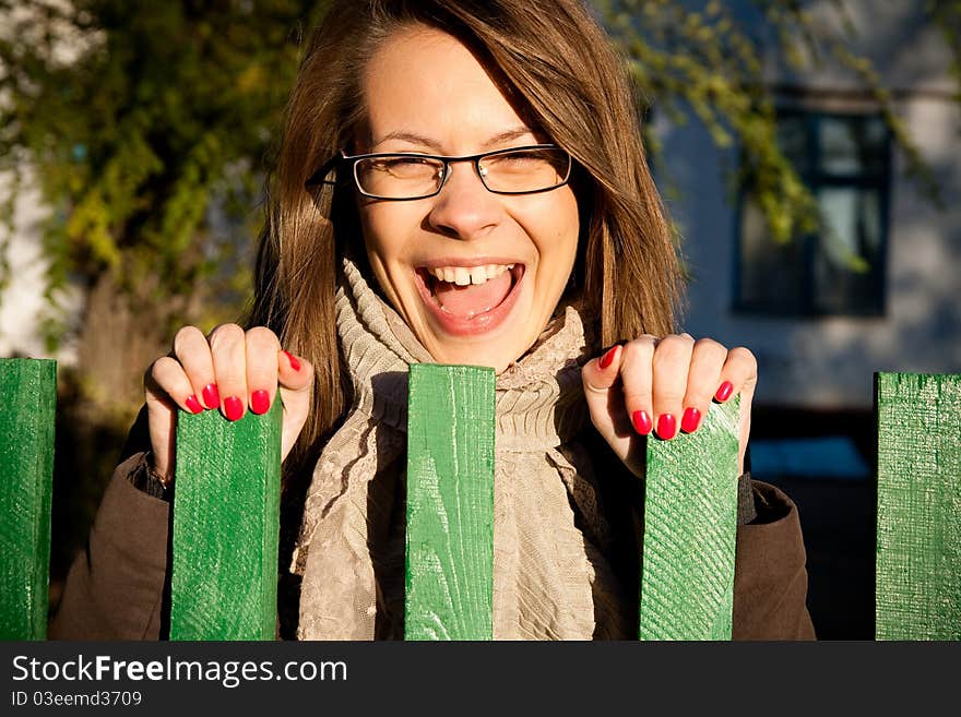 Teenage girl is laughing at green fence on the street. Teenage girl is laughing at green fence on the street.