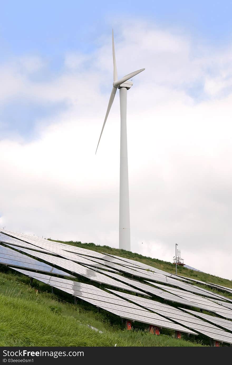 Solar panel and wind mill in front of a tree and blue sky. Solar panel and wind mill in front of a tree and blue sky