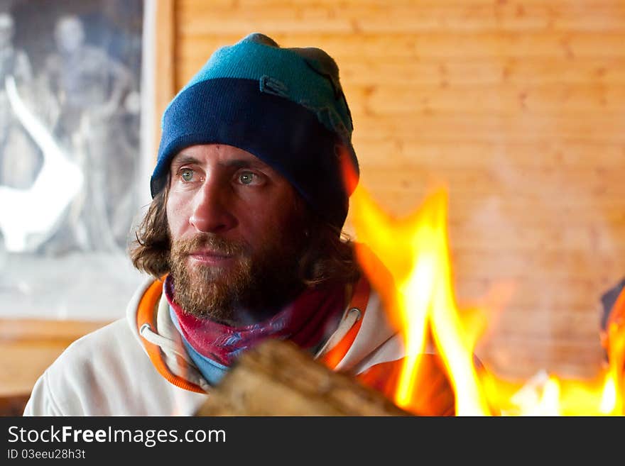 A man with long hair near a fire. A man with long hair near a fire