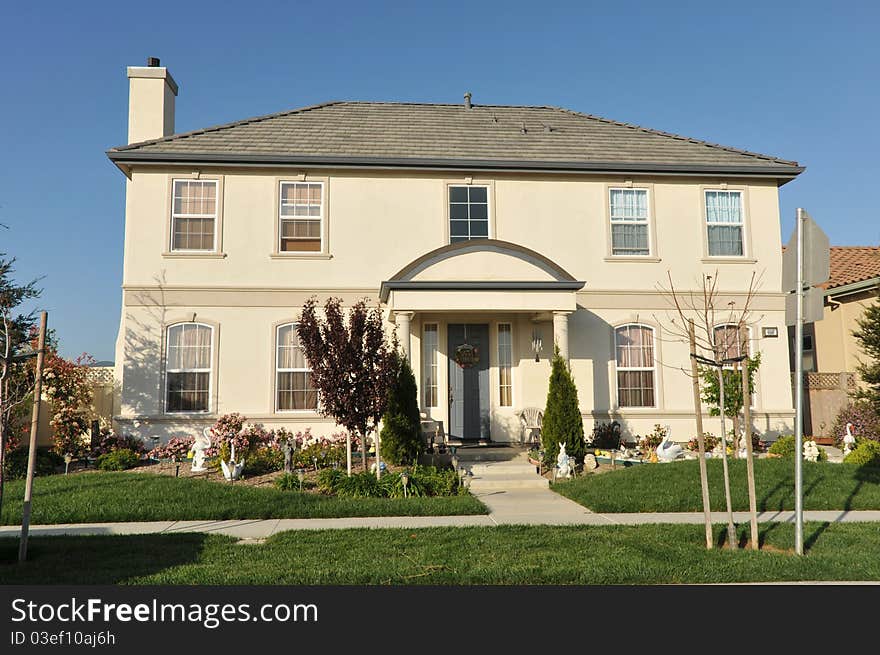 House surrounded by trees and grass with blue sky.