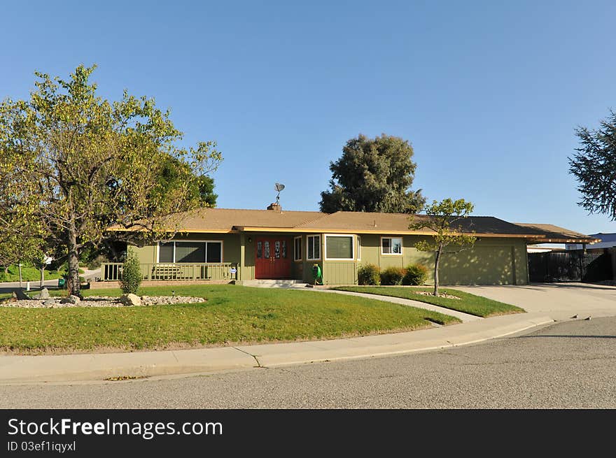 House surrounded by trees and grass with blue sky.