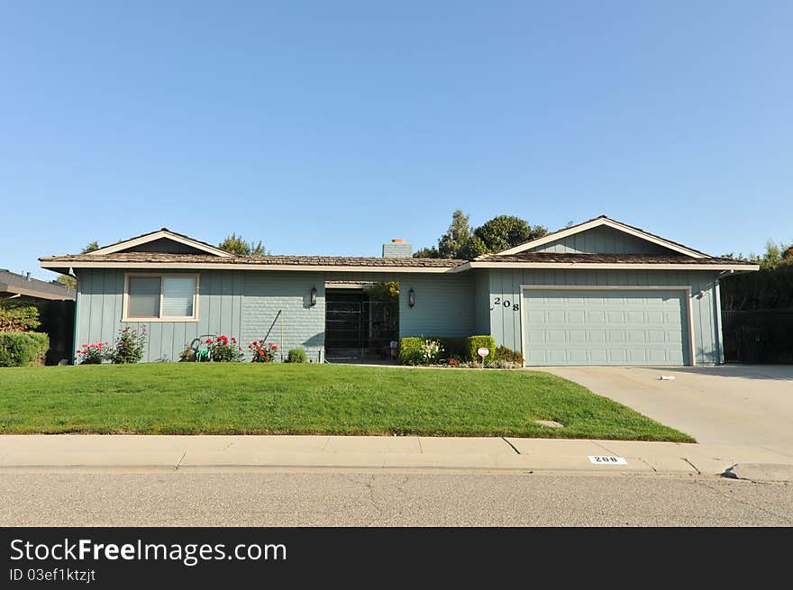 House surrounded by trees and grass with blue sky.