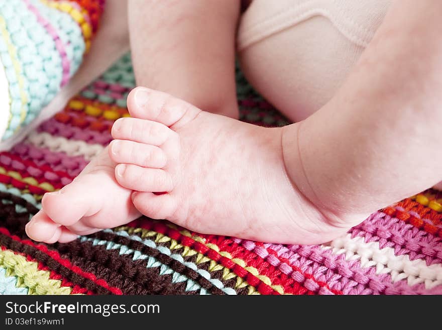 Cute newborn baby girls feet and toes on a striped blanket. Cute newborn baby girls feet and toes on a striped blanket