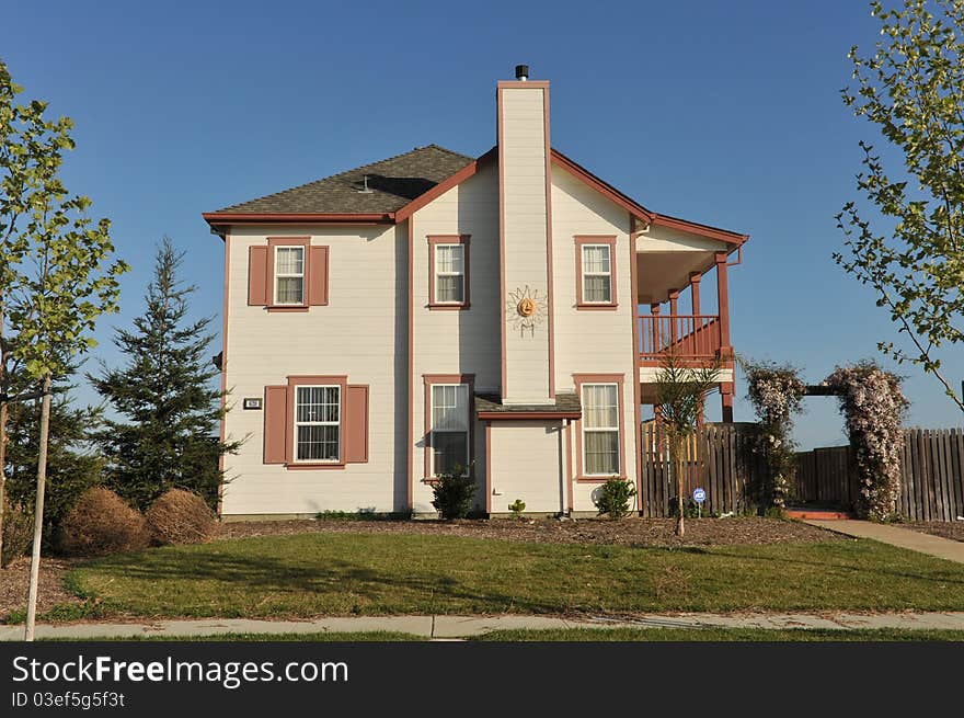 House surrounded by trees and grass with blue sky.