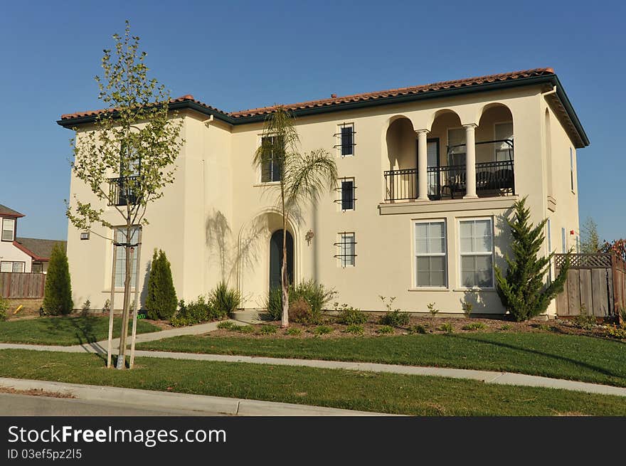 House surrounded by trees and grass with blue sky.