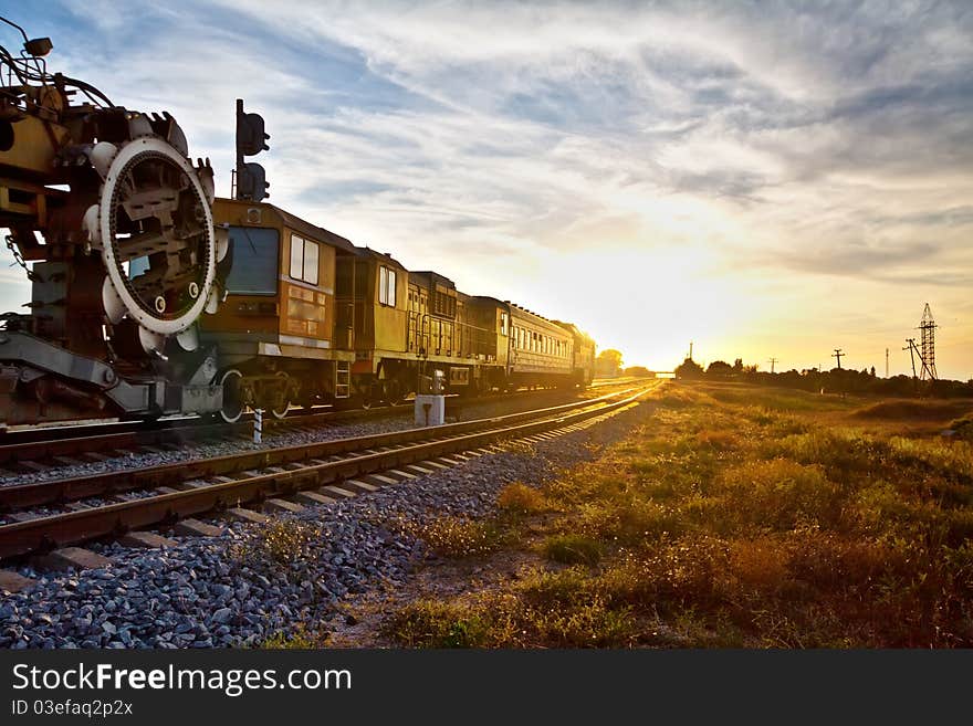 Train locomotive with industrial mechanism traveling during sunset