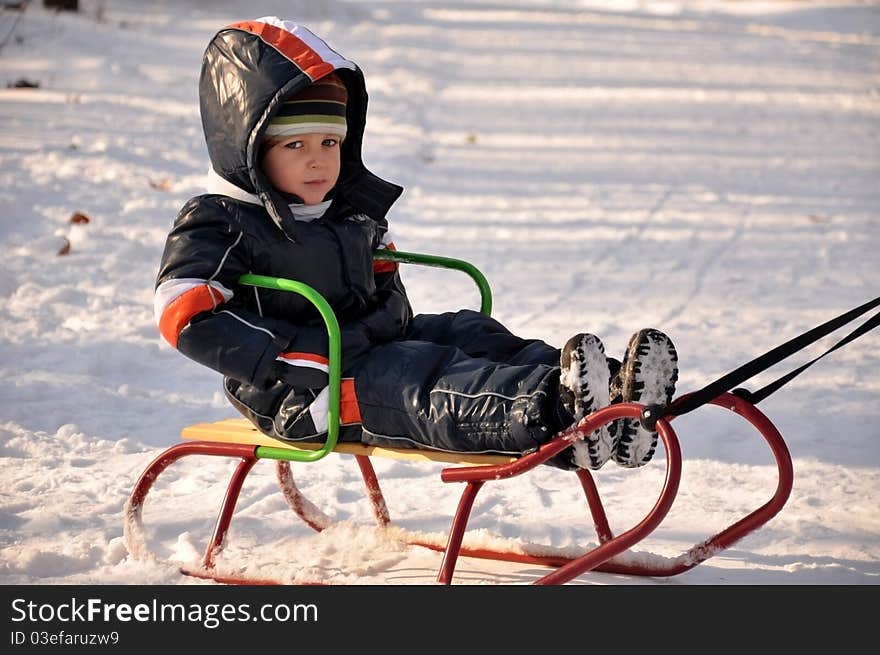 Boy smiling happy having a good time sledding. Boy smiling happy having a good time sledding