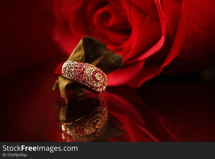 Ring with diamonds & red rose on the bacground