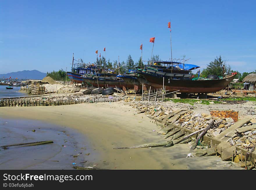 Fishing boat Lamparo at anchor. All boats are identical in the Vietnamese fishing fleet. They are made of wood painted blue with a reminder of the country's symbol is the dragon. In his bow with a red dot for fire and on the flat edge of the eye of the dragon . The red flag with yellow star is always at the end of the bamboo pole. Fishing boat Lamparo at anchor. All boats are identical in the Vietnamese fishing fleet. They are made of wood painted blue with a reminder of the country's symbol is the dragon. In his bow with a red dot for fire and on the flat edge of the eye of the dragon . The red flag with yellow star is always at the end of the bamboo pole.