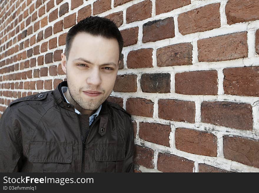 Young man in fron of the brick wall and view on the facade of the old brick wall, Prague.