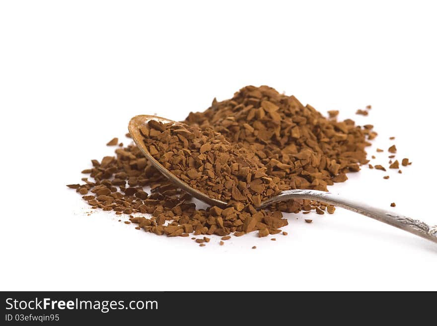 Instant coffee granules in spoon over white