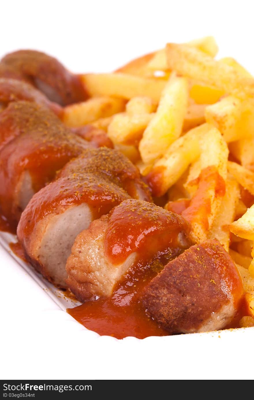 A bowl with curried sausage and chips in front of white background