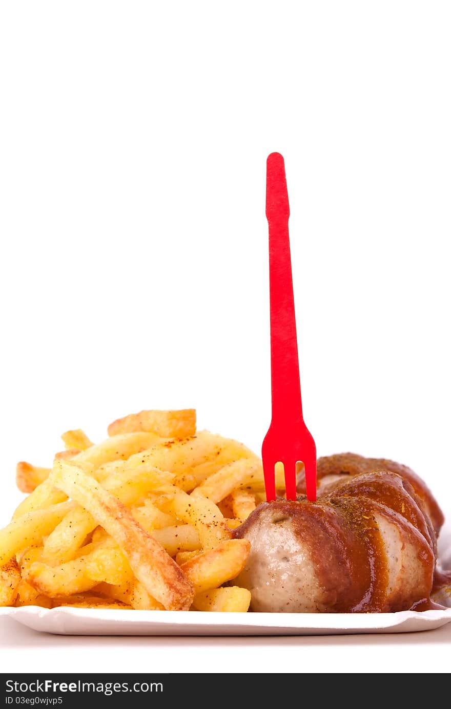 A bowl with curried sausage and chips in front of white background