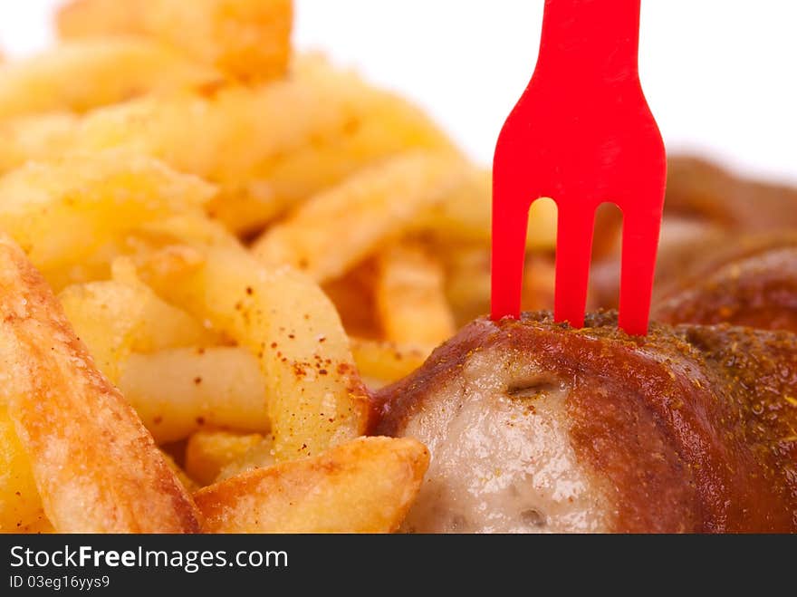 Curried sausage with chips and a red fork. Curried sausage with chips and a red fork