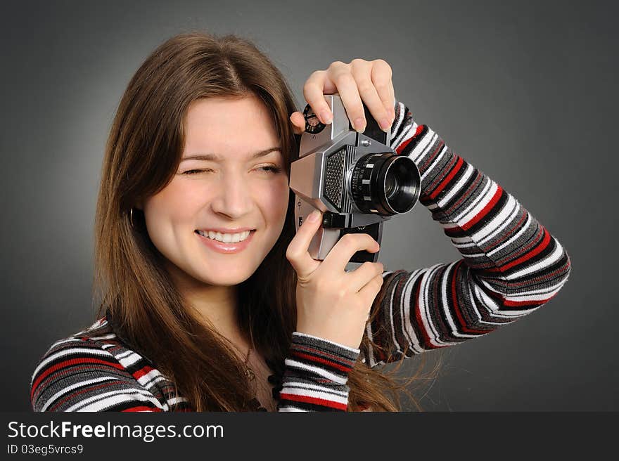 Pretty woman with vintage camera on a grey background. Pretty woman with vintage camera on a grey background