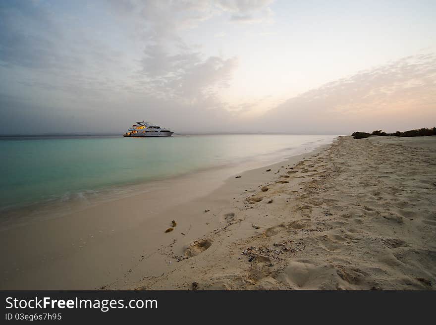 Tropical beach at dusk with sunset and boat in the background. Tropical beach at dusk with sunset and boat in the background