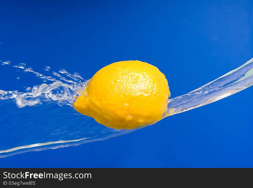 Fresh lemon in the splashes of water on a blue background