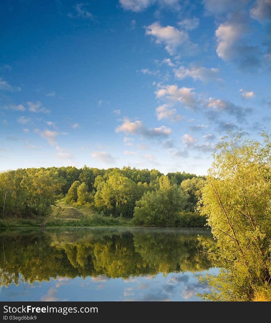 Summer landscape with river and pink clouds on blue sky. Summer landscape with river and pink clouds on blue sky.