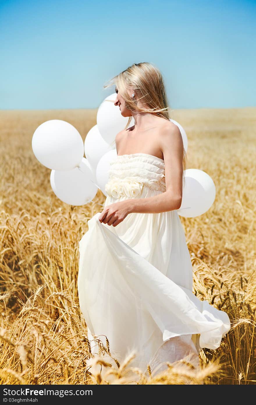 Blond smiling girl with white balloons in the field. Blond smiling girl with white balloons in the field