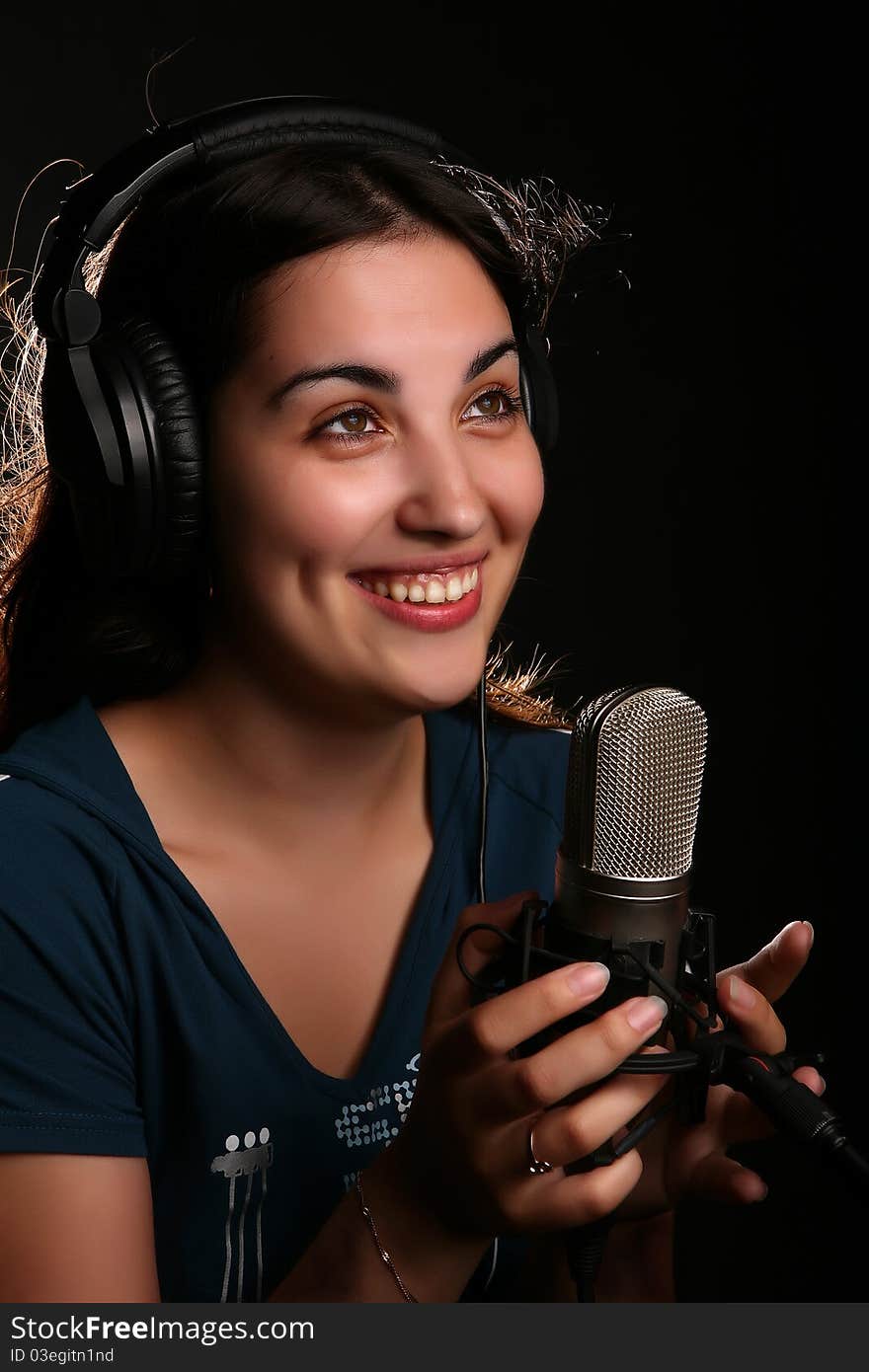 Singin' girl with a microphone and head-phones on the black background