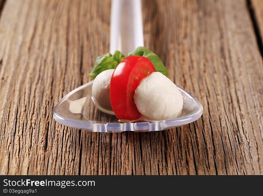 Mozzarella cheese balls and tomato on a salad spoon