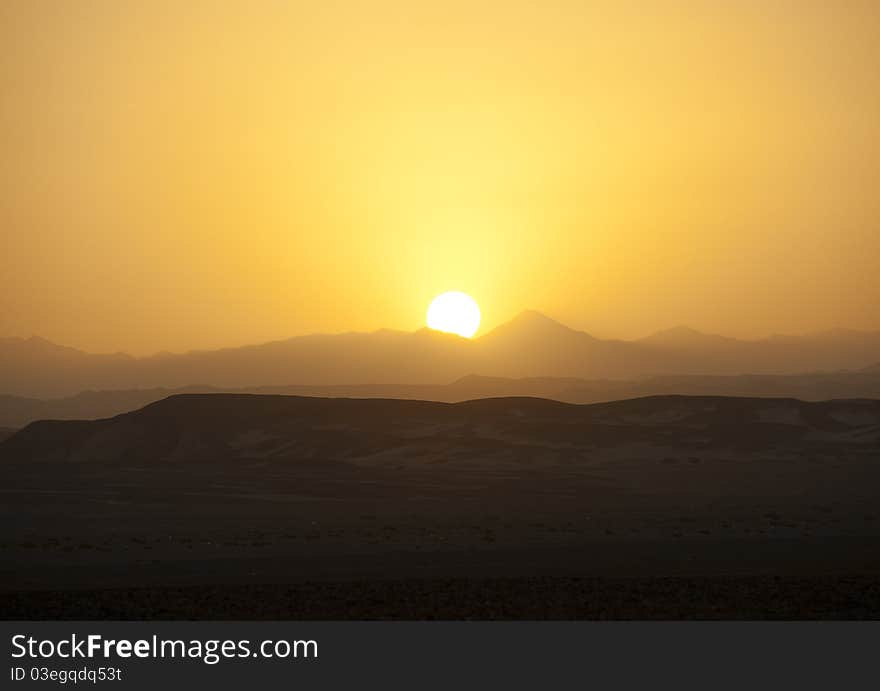 Sun setting in the desert over distant mountains. Sun setting in the desert over distant mountains