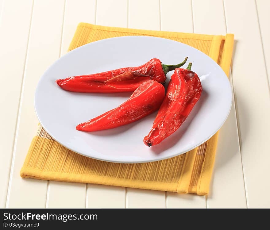 Three roasted red peppers on a plate. Three roasted red peppers on a plate