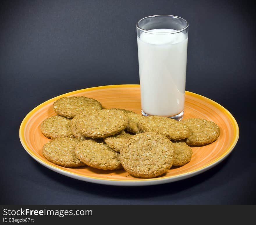 A close up of plain biscuits, and a glass of milk on an orange plate. A close up of plain biscuits, and a glass of milk on an orange plate