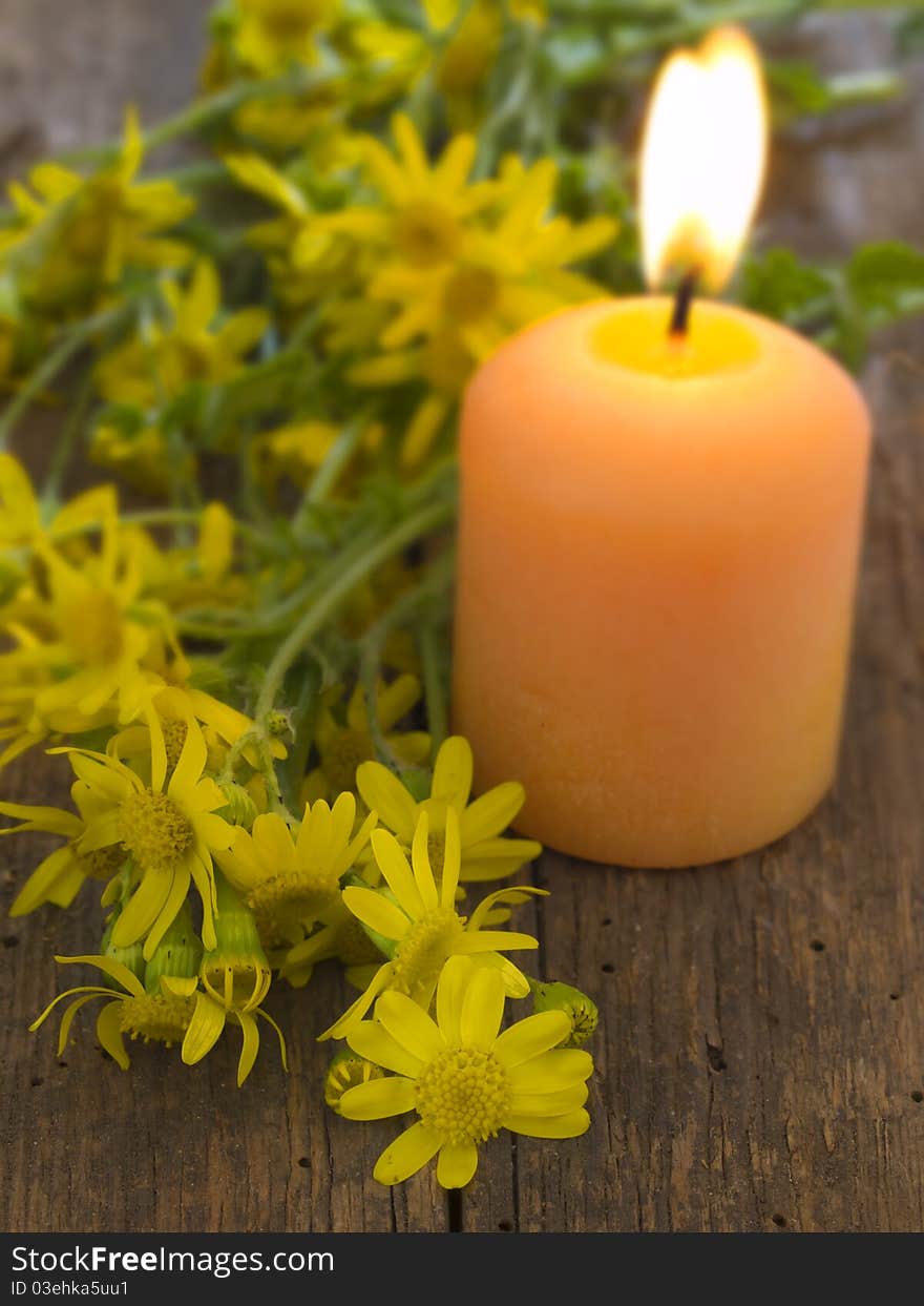 With burning candle and yellow flowers over wood background. With burning candle and yellow flowers over wood background