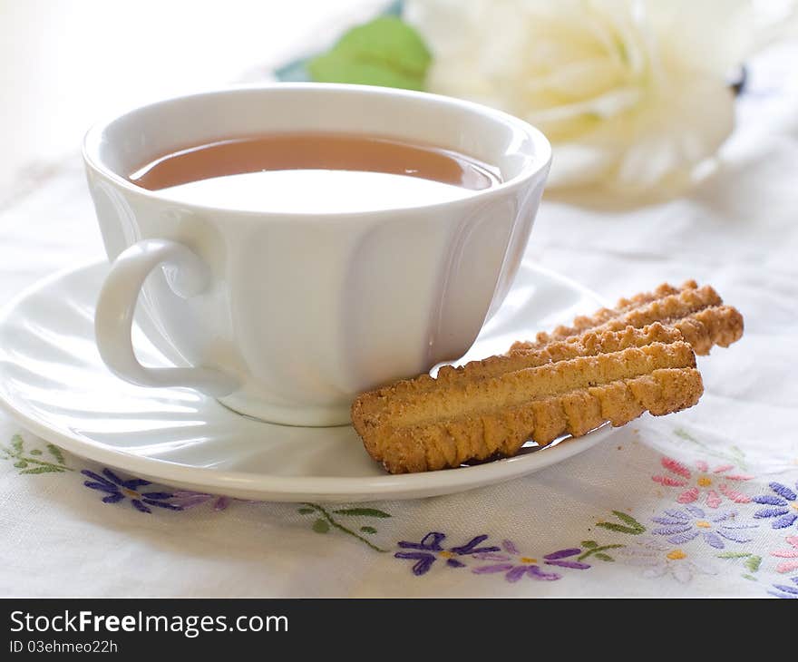 A cup of tea with cookies and tulip