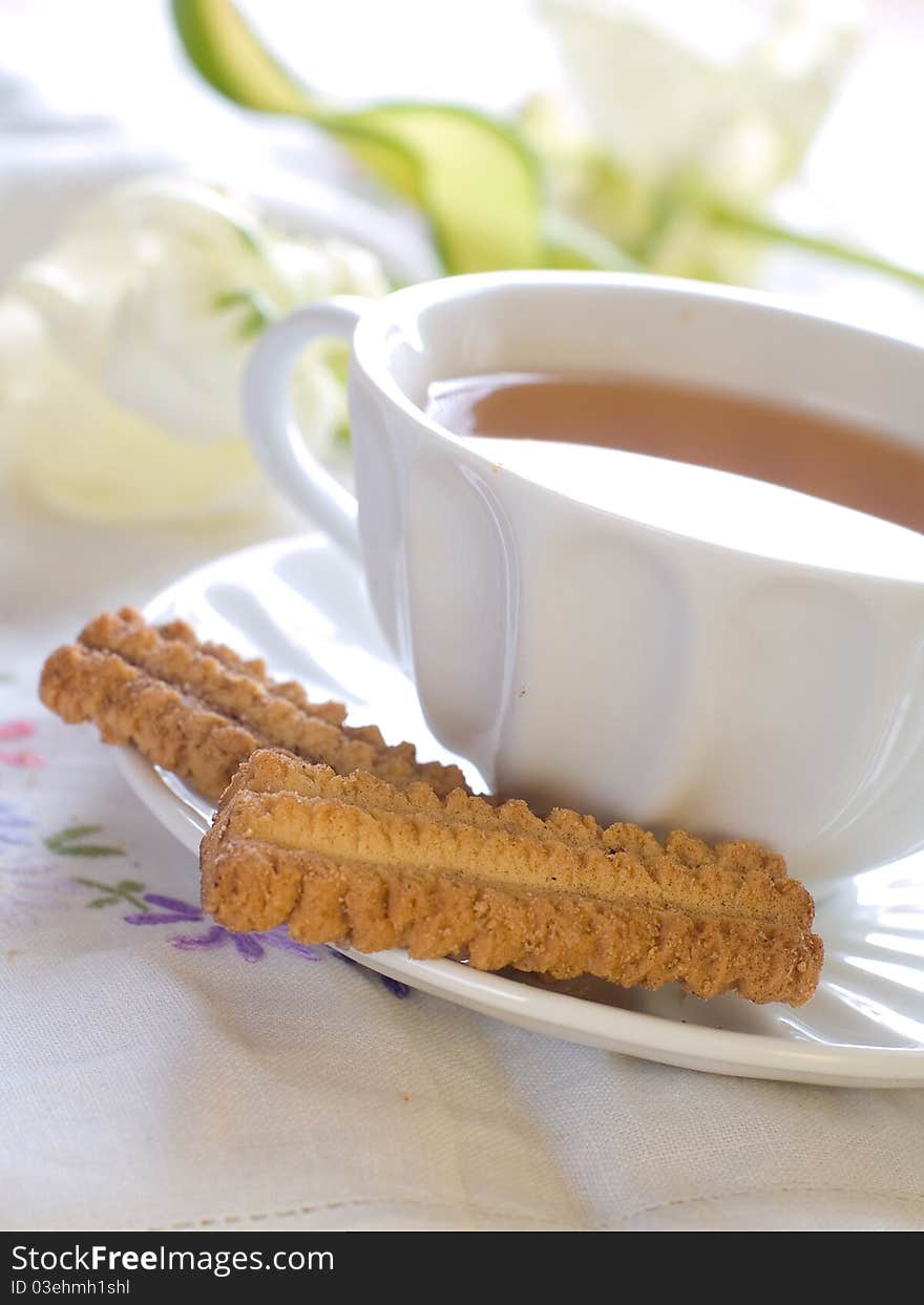 A cup of tea with cookies and tulip