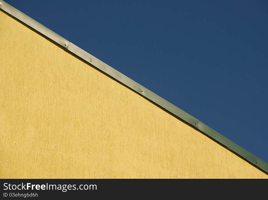 Fragment of the yellow roof of the build and blue sky. Fragment of the yellow roof of the build and blue sky