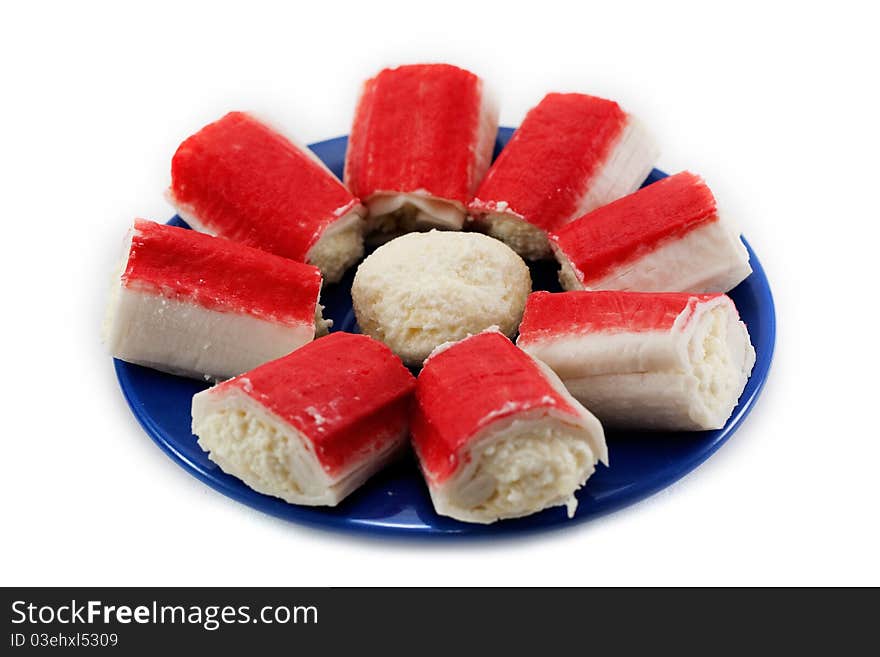 A dish of crab sticks on the blue plate isolated on white background. A dish of crab sticks on the blue plate isolated on white background