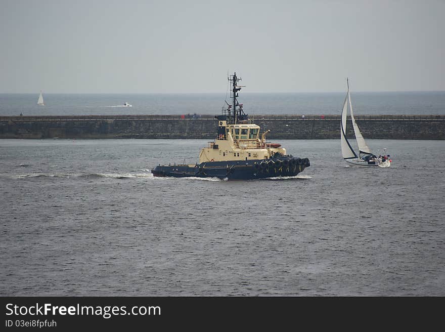 Powerful tug boat passing small yacht on river Tyne. Powerful tug boat passing small yacht on river Tyne