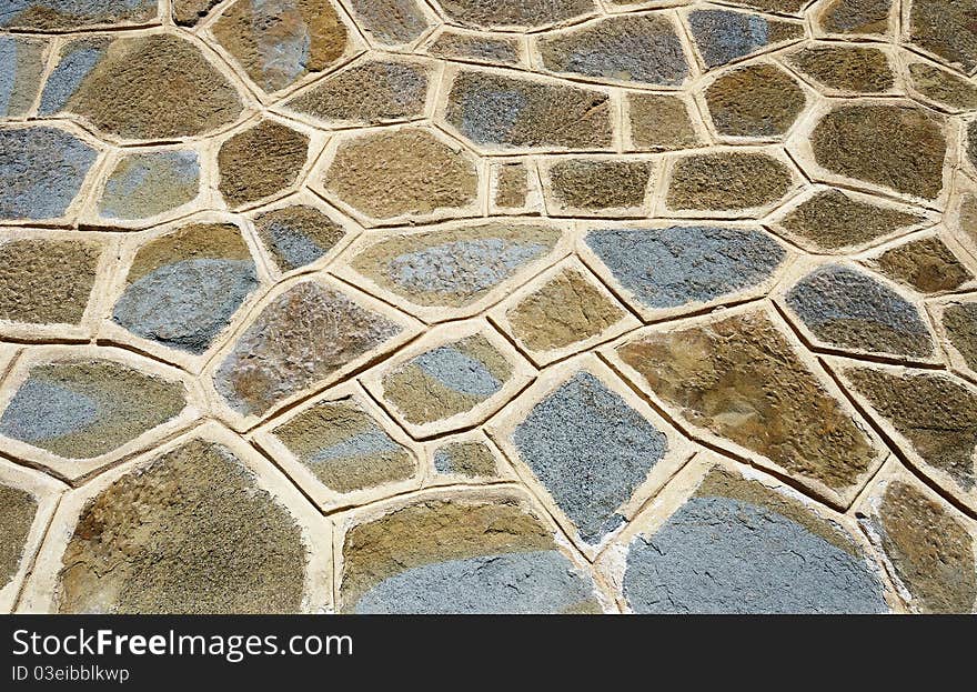 A rough wall made of colored cemented stones. A rough wall made of colored cemented stones