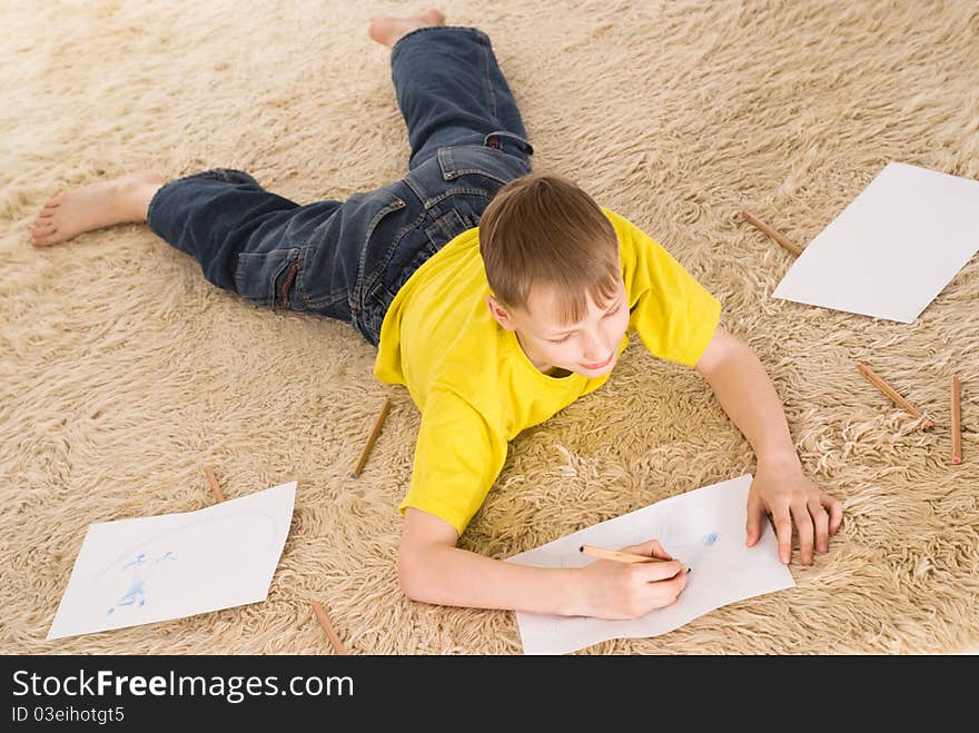 Young boy drawing on the carpet on white