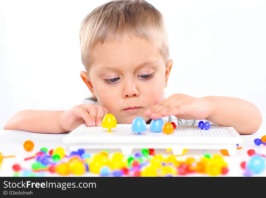 Little boy playing with multicolored mosaic isolated on a white background. Little boy playing with multicolored mosaic isolated on a white background