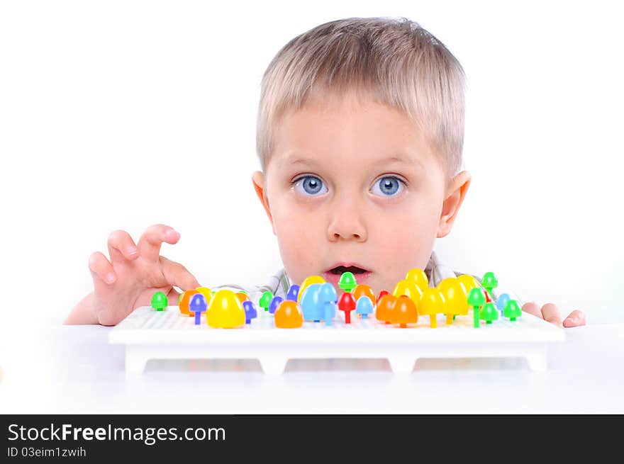 Little boy playing with multicolored mosaic isolated on a white background. Little boy playing with multicolored mosaic isolated on a white background