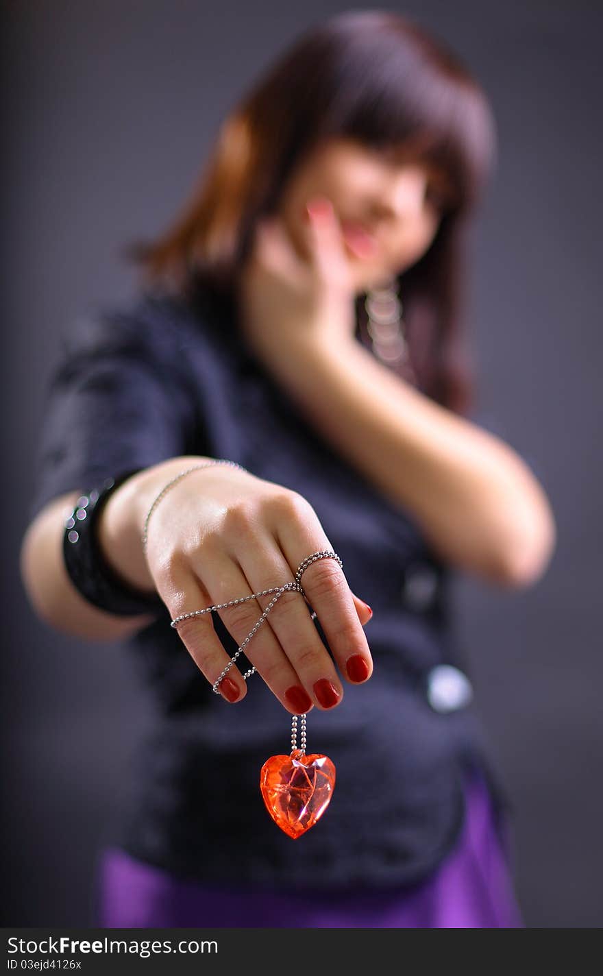 Young beautiful woman holding heart, isolated on dark background - focus on heart