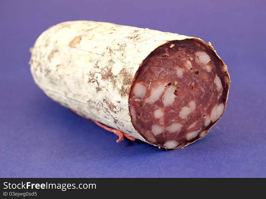 Milan salami cut in the foreground color background