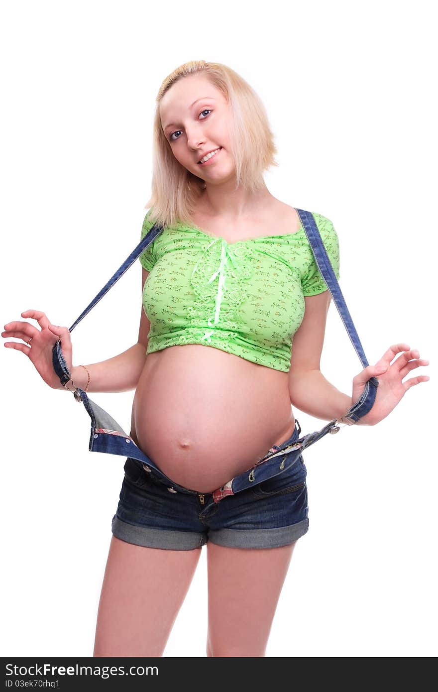 Young pretty pregnant woman posing in jeans overalls