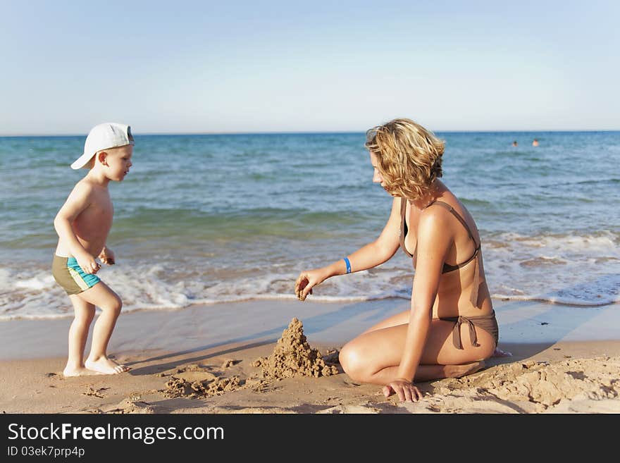 Mom and son building a sand castle on a beach